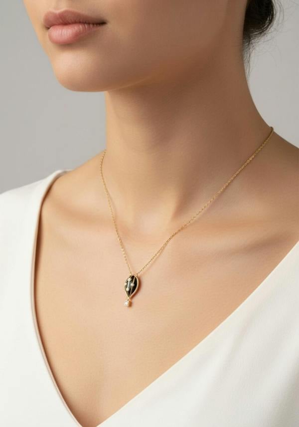 Necklace with a black hot air balloon pendant worn by a person against a neutral background