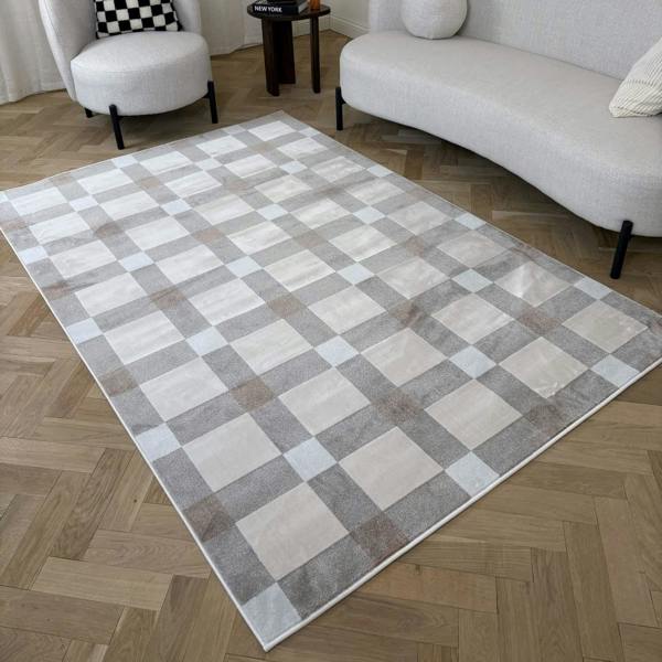 Checkered area rug on a wooden floor with a sofa and chair in the background