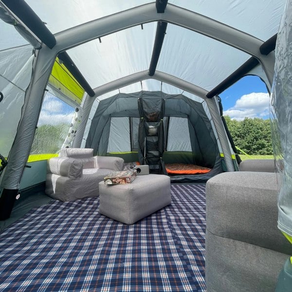 An image from the inside of the OLPRO Home 5 Berth Inflatable Family Tent showing some camping furniture and the inner tent with sleeping bags inside.