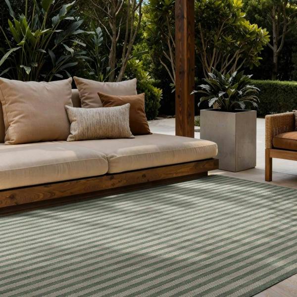 Outdoor seating area with a striped rug, cushions, and plants.