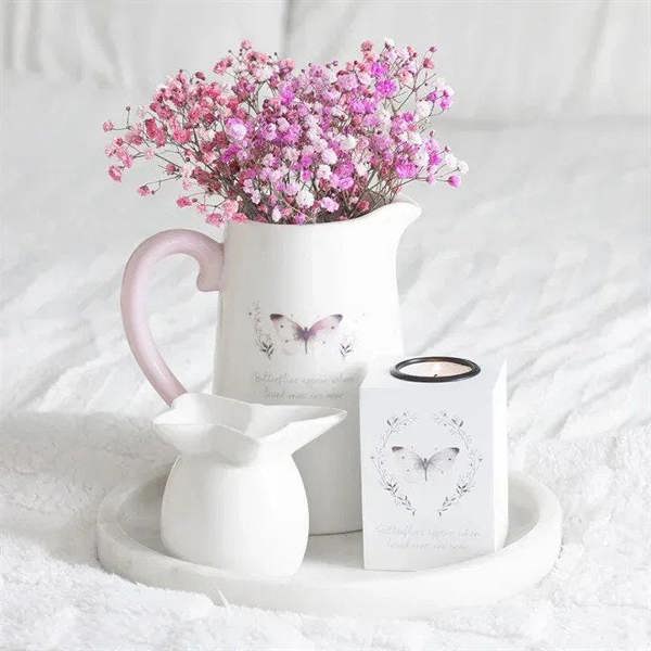White ceramic flower jug with pink handle, butterfly print, holding pink flowers