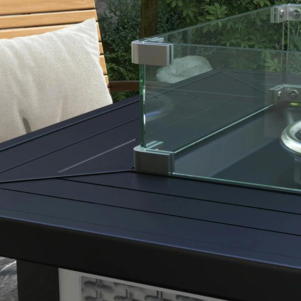 Grey gas fire pit table with clear glass wind guard and dark burner tray