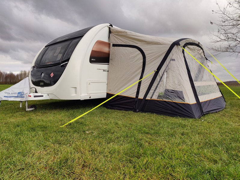 The OLPRO View Lite Breeze 390 Caravan Awning pictured in a Caravan site attached to a caravan with the doors closed.