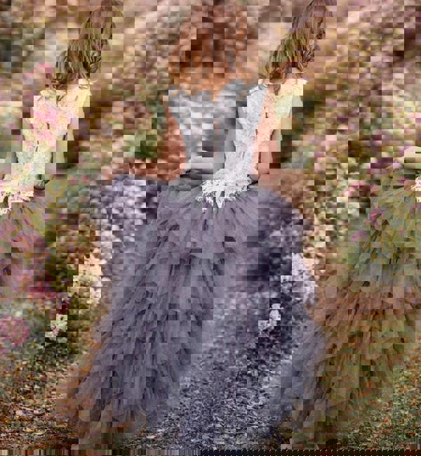 Young girl in a floral dress standing in a cherry blossom garden
