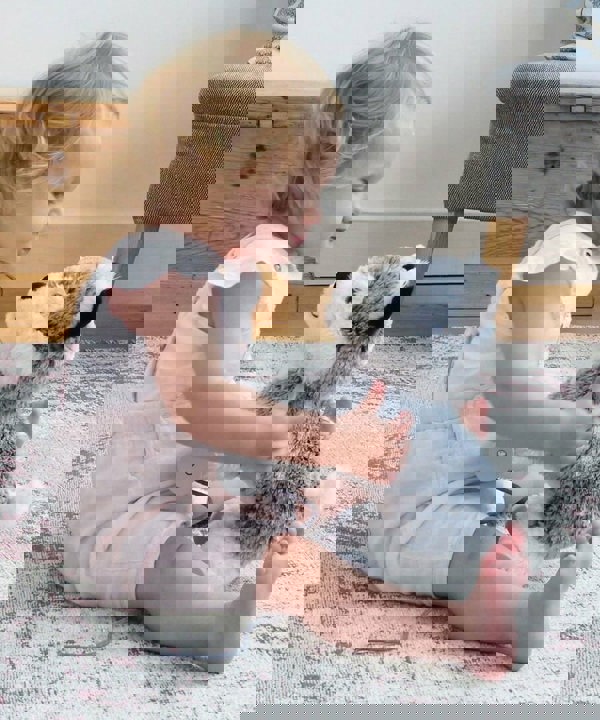 Baby Girl sat with Mishka Dog Pull Along Toy with white and silver plush fluffy fabric