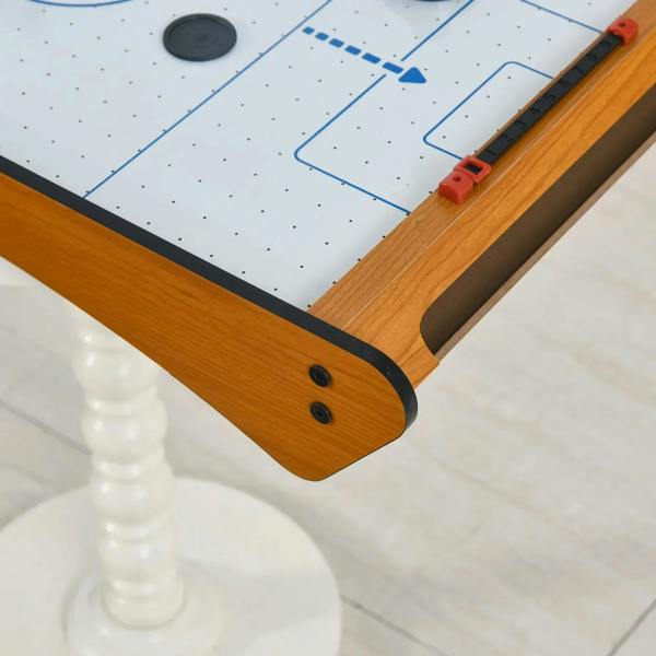 Corner close-up of wooden tabletop air hockey table with red goal pusher