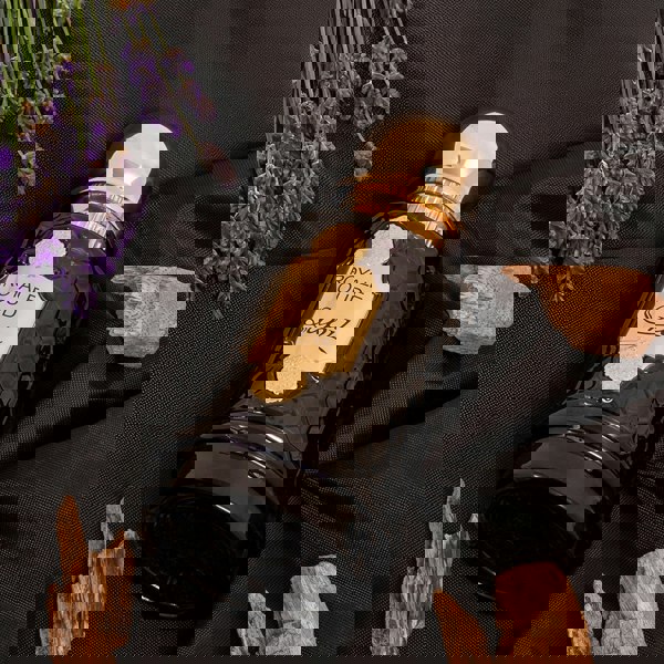 Sapil Royale Oud bottle lying on fabric with lavender and wood