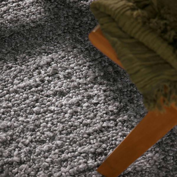 Gray textured carpet with a green and orange object partially visible