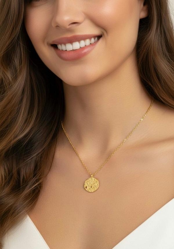 Close-up of a woman wearing a gold necklace with a pendant.