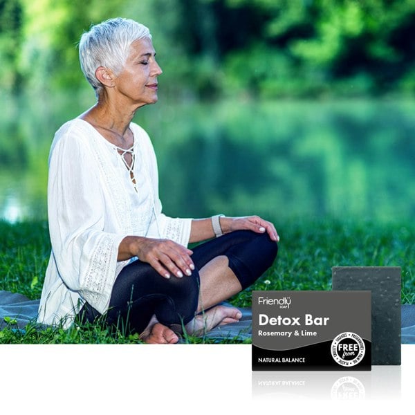 Woman sat in lotus position with foliage in the background