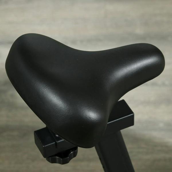 Black padded saddle seat with mounting base on an indoor cycling bike