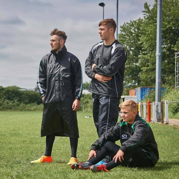 Three men on a grass pitch wearing black Optimum sideline sub jackets and tracksuits - Optimum