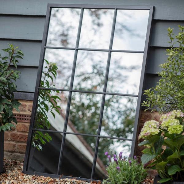 The 120x80cm large rectangular black metal window pane mirror mounted landscape on a brick garden wall by Abode Home & Gifts.