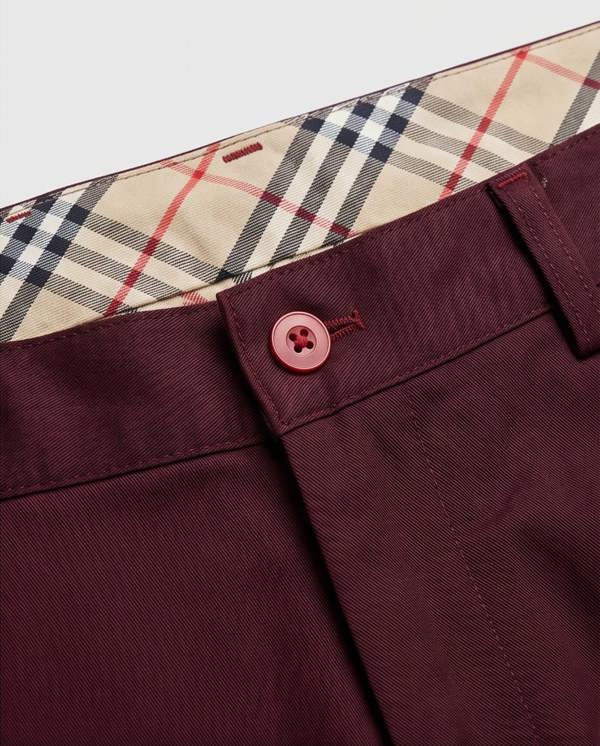 Close-up of maroon pants with a plaid lining on a white background