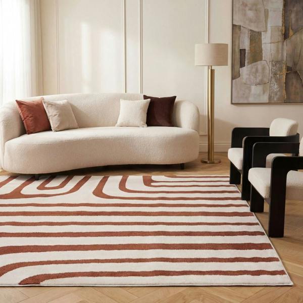 Modern living room with a striped rug, beige sofa, and abstract art on the wall.