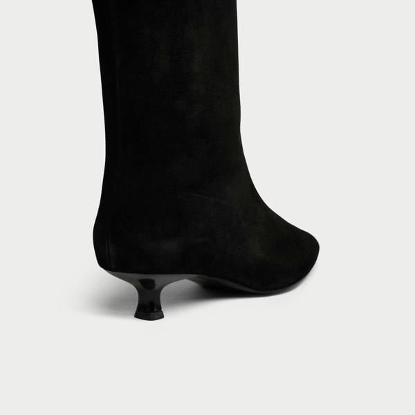 Black knee-high boot with a thin heel on a light gray background