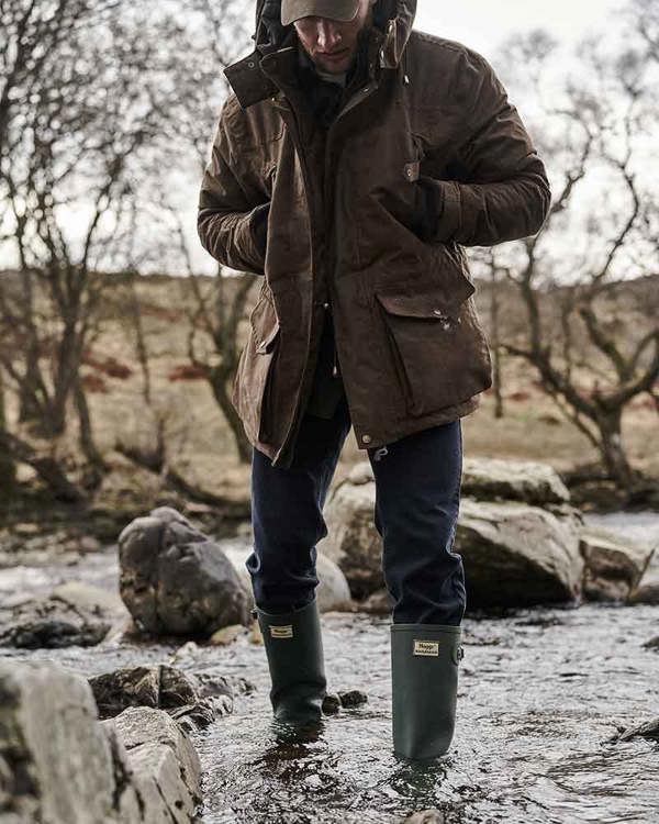 Man crossing shallow river in Hoggs of Fife Braemar wellies showcasing waterproof protection and grip