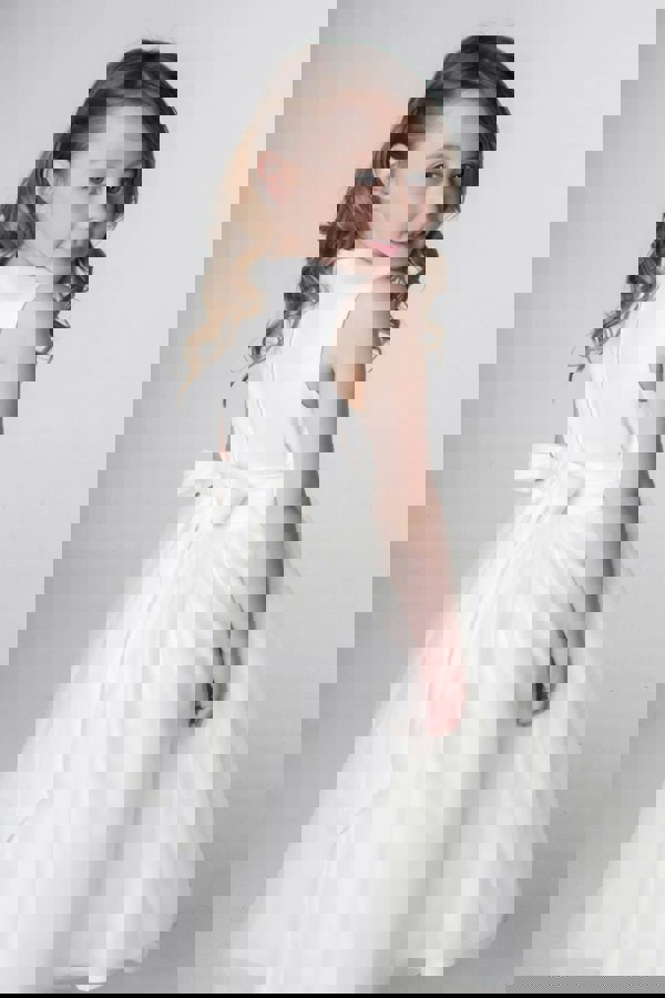 Young girl wearing a Ivory dress against a plain background