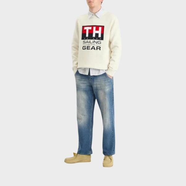 Supplied Fashion white crewneck knit sweater with nautical logo graphic worn with blue jeans and tan shoes