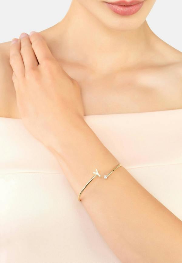 A bangle in the shape of a letter Y on a person's wrist with a plain background