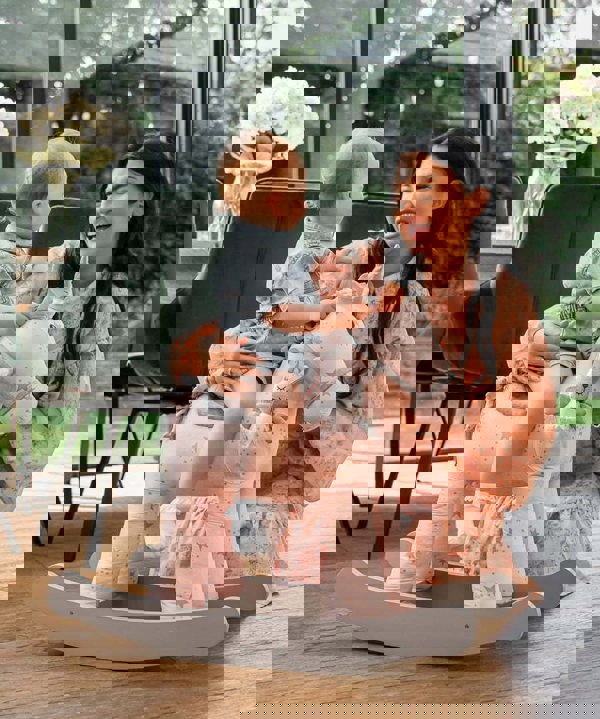 girl and mum playing with pink rocking unicorn toy 