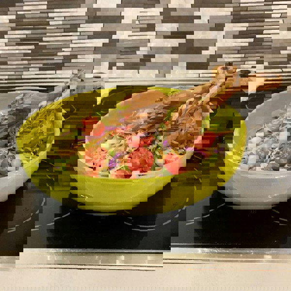 Olive wood serving tongs in a bowl of salad