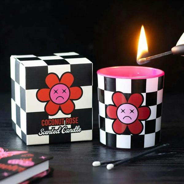 Checkered black-and-white scented candle in metal tin with lit flame and pink wax top