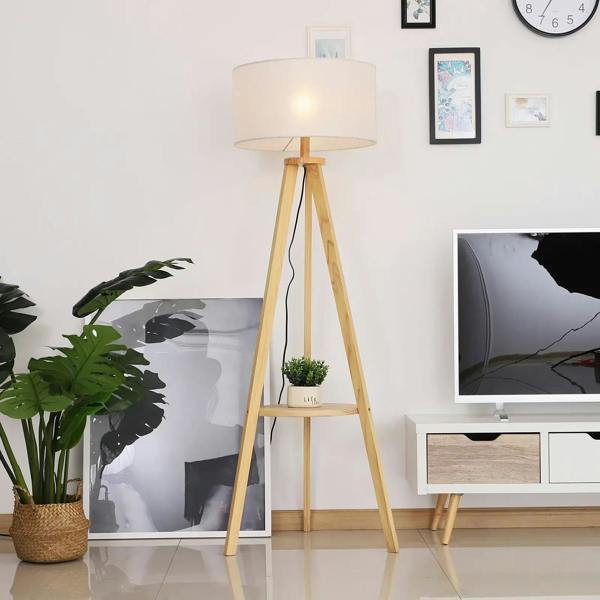Tripod floor lamp with cream fabric shade and round storage shelf on wooden legs