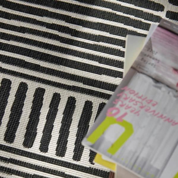 Close-up of a black and white striped fabric with a product packaging in the foreground.