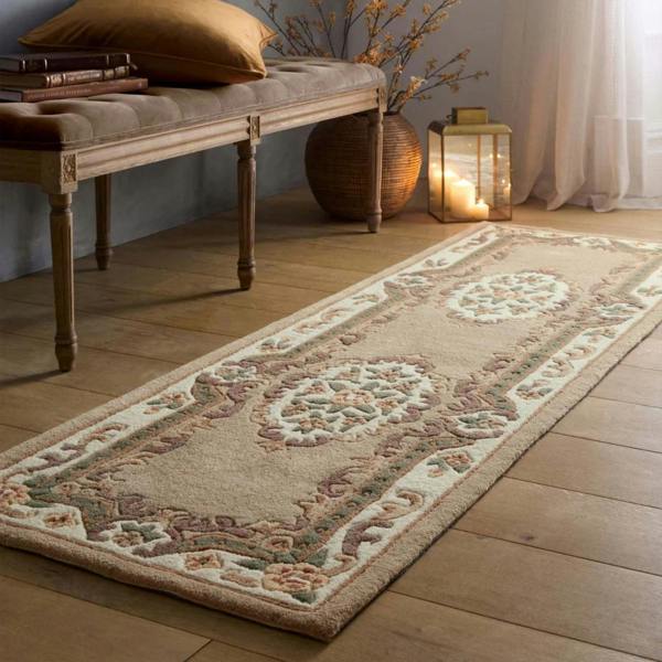 Decorative rug on a wooden floor with a bench and candles in the background