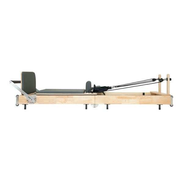 Pilates reformer machine in oak wood with a sleek design, gray padded platform, and adjustable resistance cables for versatile workouts