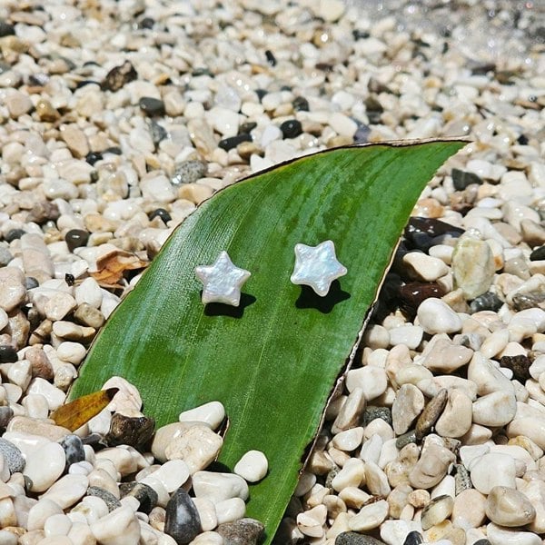 Unique pearl star stud earrings with a beachside backdrop.