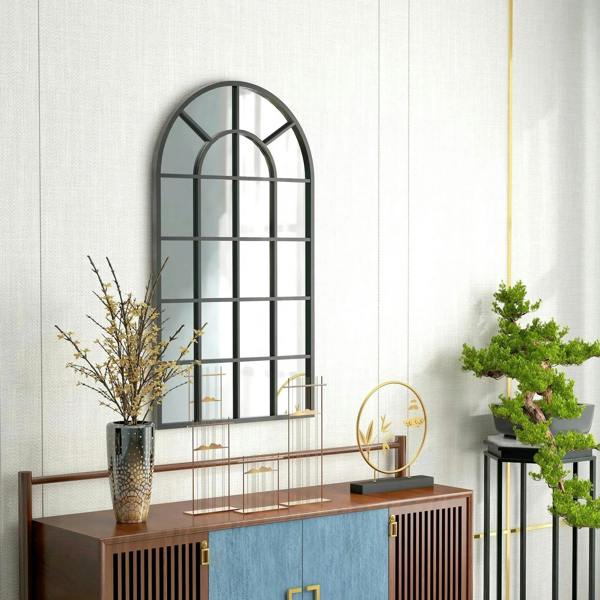 Black arched wall mirror with window grid pattern above a wood console table