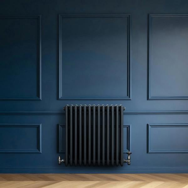 Anthracite grey traditional 4 column radiator mounted on a deep blue wall, featuring sleek valves and a smooth, modern finish