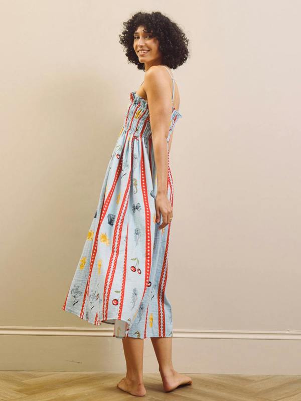 Woman wearing a colorful nightdress with a pattern against a beige wall.