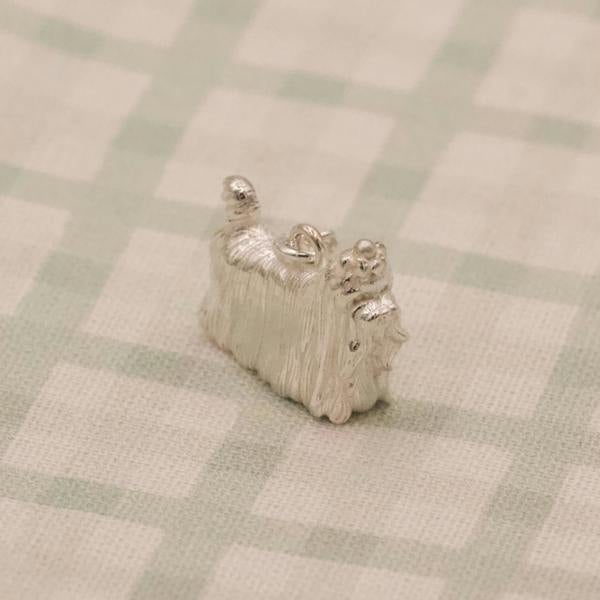 Small silver yorkshire terrier figurine on a checkered fabric background