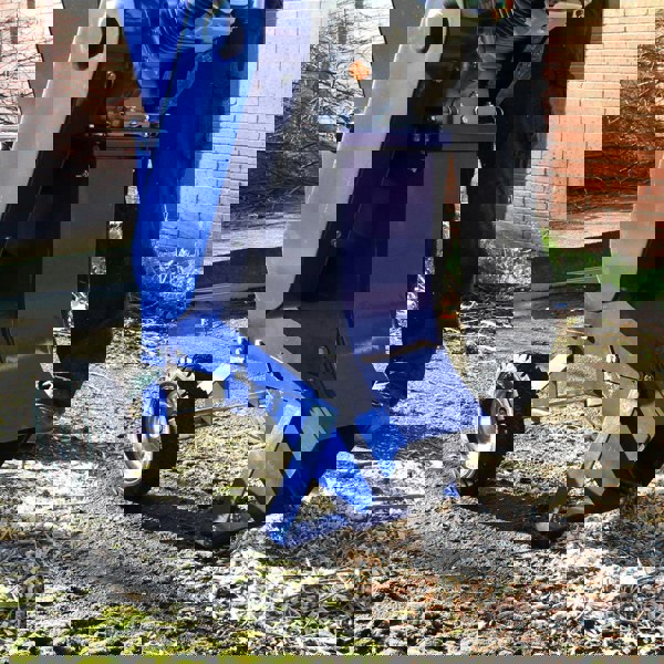 Blue T-Mech 15HP wood chipper with a sturdy frame, large chute, and wheels, positioned on a gravel surface with wood chips scattered around