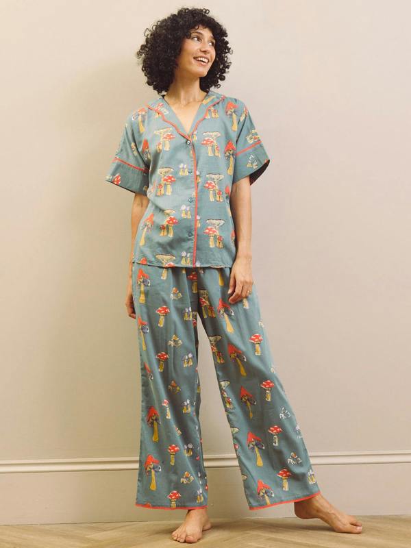 Woman wearing a mushroom patterned oversized pyjama set against a plain background