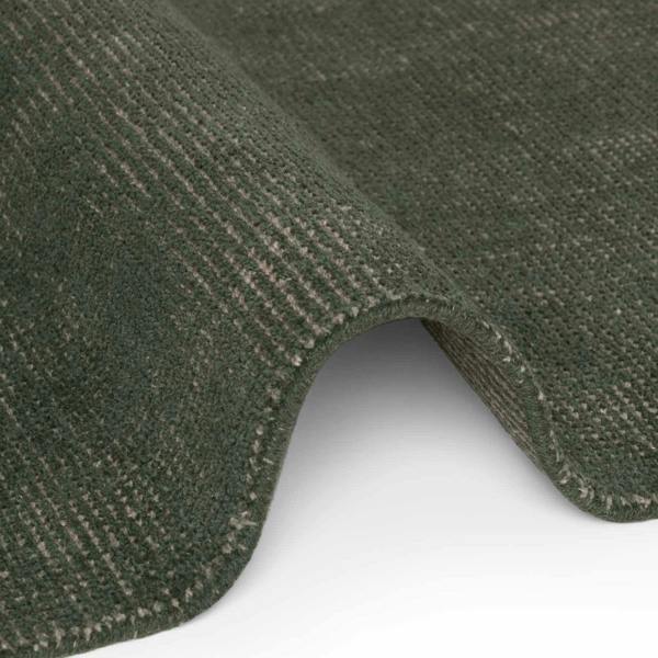Close-up of a green textured rug corner on a white background