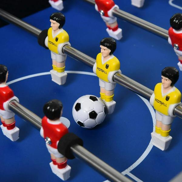 Foosball table close-up with yellow players, red players, and a white soccer ball