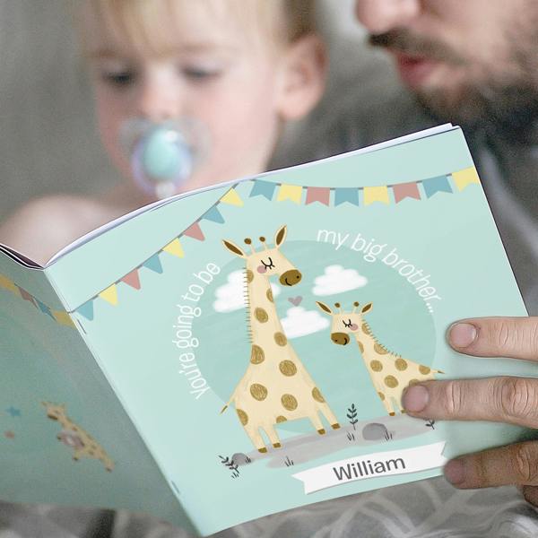 A father reading a light blue Personalised Big Brother Story Book featuring a giraffe illustration and the name William to his toddler son.