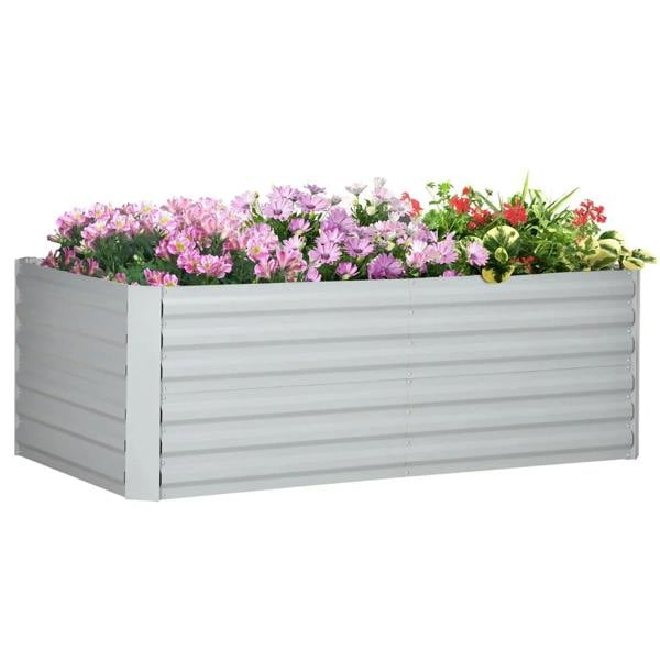 Light grey raised garden bed planter filled with pink and red flowers and green foliage
