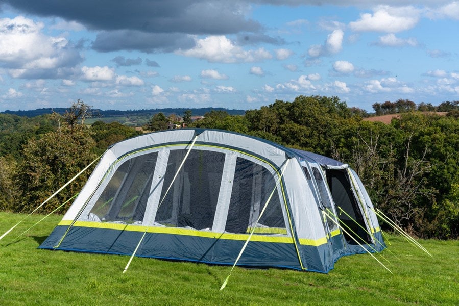 The OLPRO Odyssey  Breeze® Inflatable 8 Berth Tent pitched in a campsite with a treeline in the background.