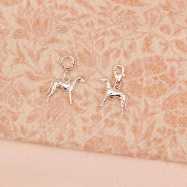 Two silver Whippet dog-shaped charms on a floral fabric background
