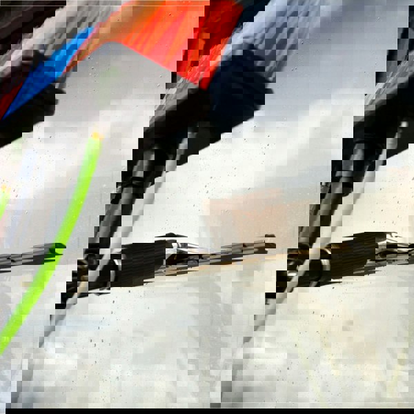 Colorful brush head with soft bristles and squeegee, attached to a water-fed pole, cleaning a glass surface outdoors