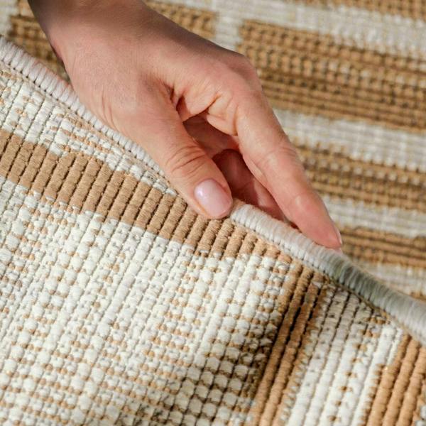 Hand touching a woven beige and white rug