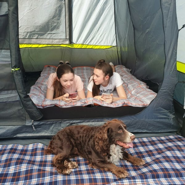 An image of two females lay in one side of the sleeping pod of the OLPRO Home 5 Berth Inflatable Family Tent.