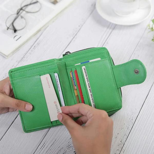 Green wallet with cards on a white wooden surface