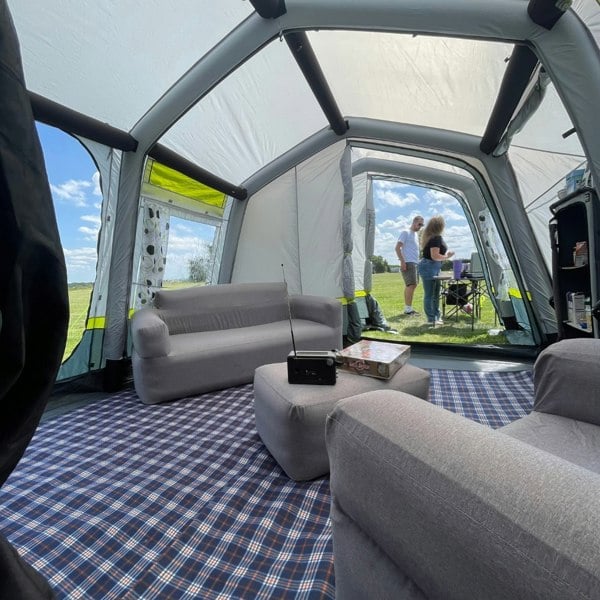 An image from the inside of the OLPRO Home 5 Berth Inflatable Family Tent showing a male and a female cooking on a stove outside of the tent.