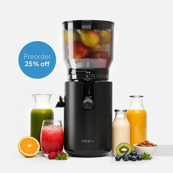 The black Fridja f2800 Open Whole Fruit Juicer with a self-feeding hopper is surrounded by fruits, nuts, and colorful juices. A blue circle displays "Preorder 25% off" on a white background.
